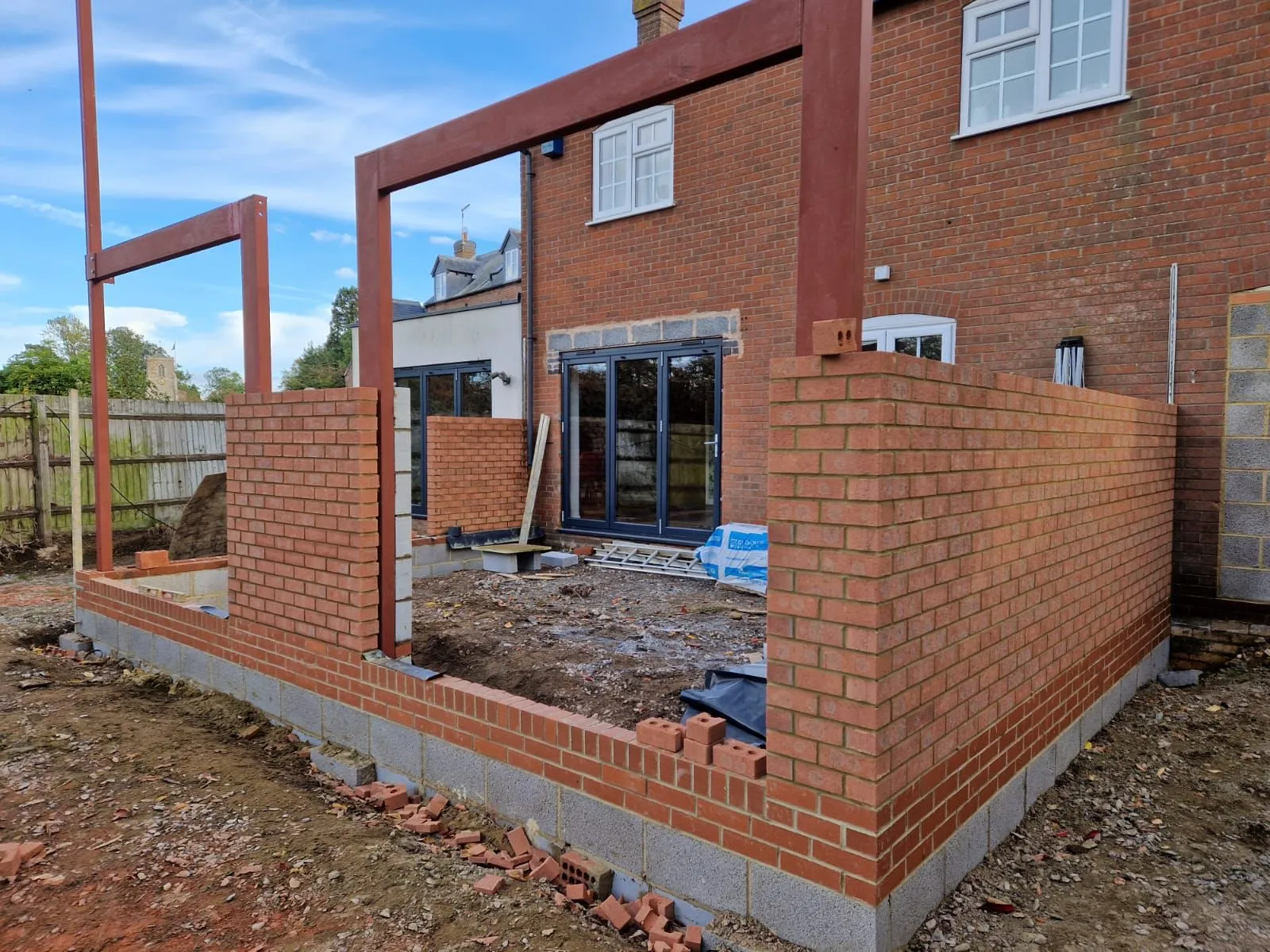 A brick house being built in the middle of a yard.